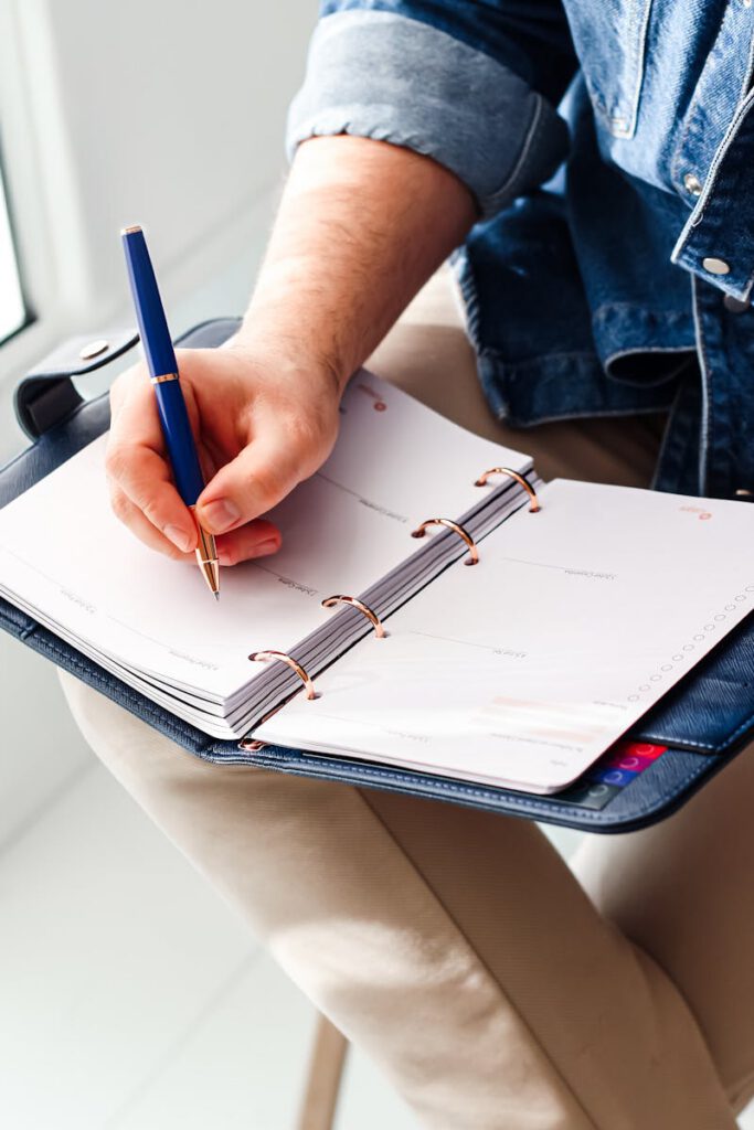 Focused image of a hand writing in a planner for schedule organization.